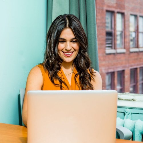 a lady in orange shirt using a laptop